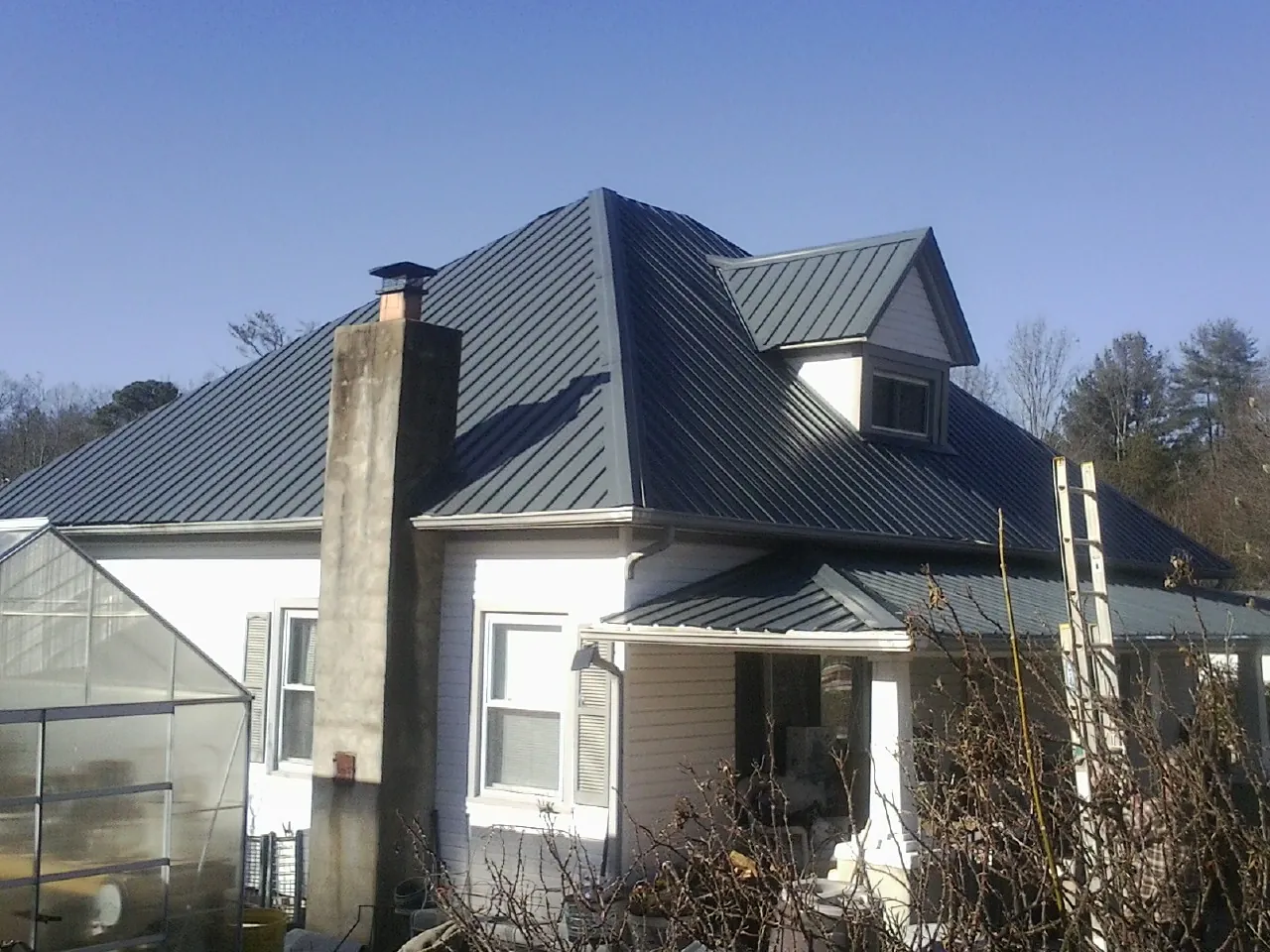 Dark blue standing seam metal roof on a white farmhouse with dormer — Slate & Tile Roof Repair by Roofing Brothers in Leipsic