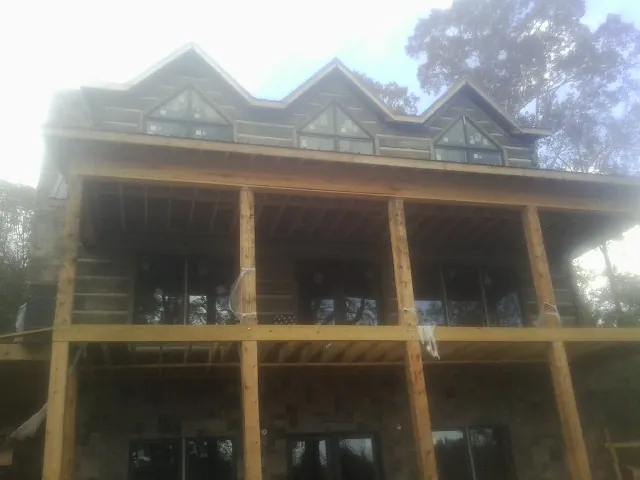 Dormers and porch framing on a large log home under construction — Roof Coating work by our crew in Leipsic