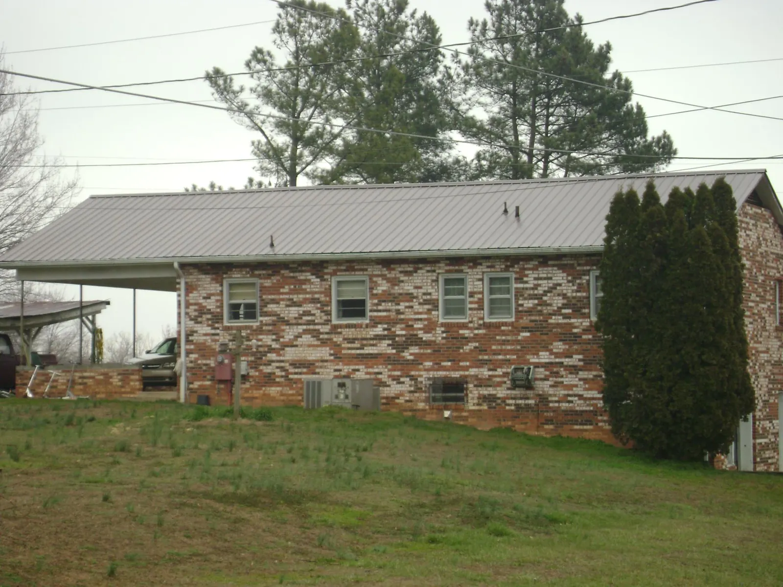 Gray metal roof on a brick split level home with a carport in Leipsic