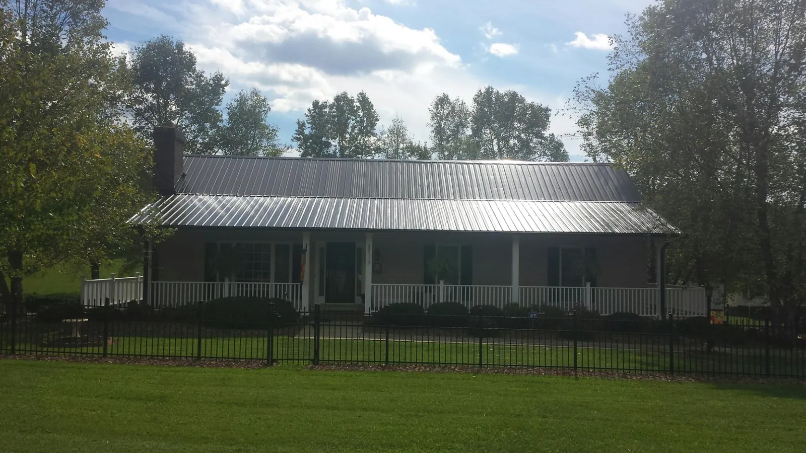 Gray metal roof on a brick ranch with a full width front porch — Gutter Guard Installation work by our crew in Leipsic